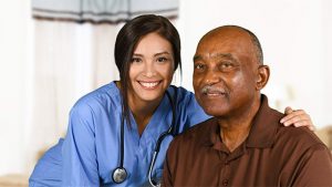 Young female nurse with arm around elderly black man.